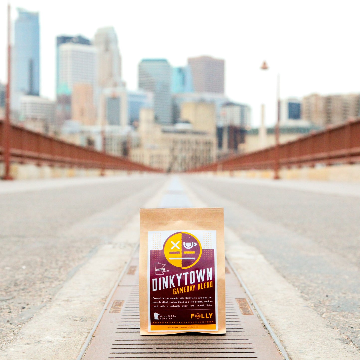 Dinkytown Athletes Gameday Blend 12oz coffee bag on city bridge with skyline background